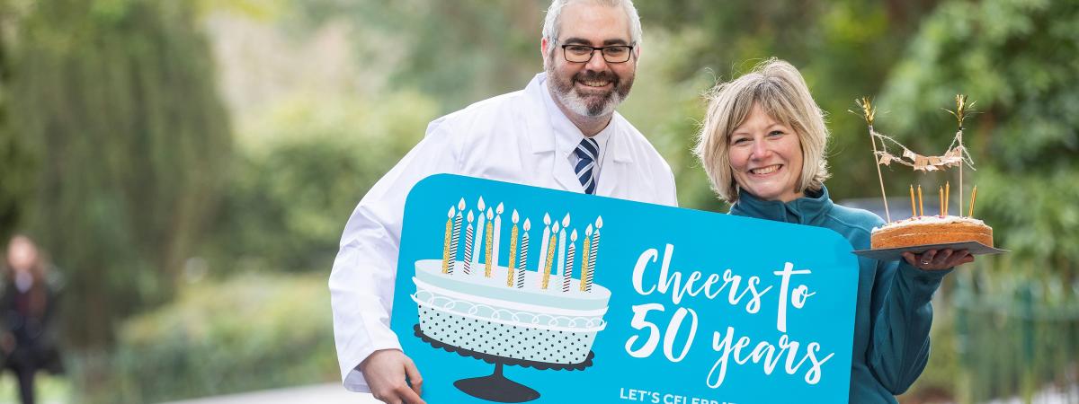 Dr Kienan Savage, senior molecular biologist at QUB, and cancer survivor Emily Stanton encourage everyone to sign up for the Cancer Focus NI Cheers to 50 Years campaign and help raise £100k for locally based cancer research.