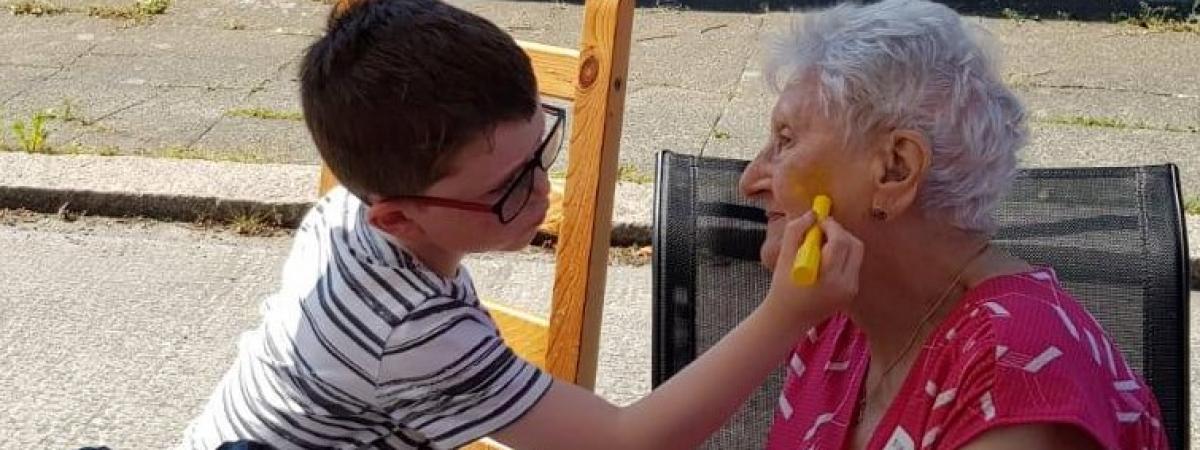 little boy paints older disabled womans face at street party held as part of The Big Lunch