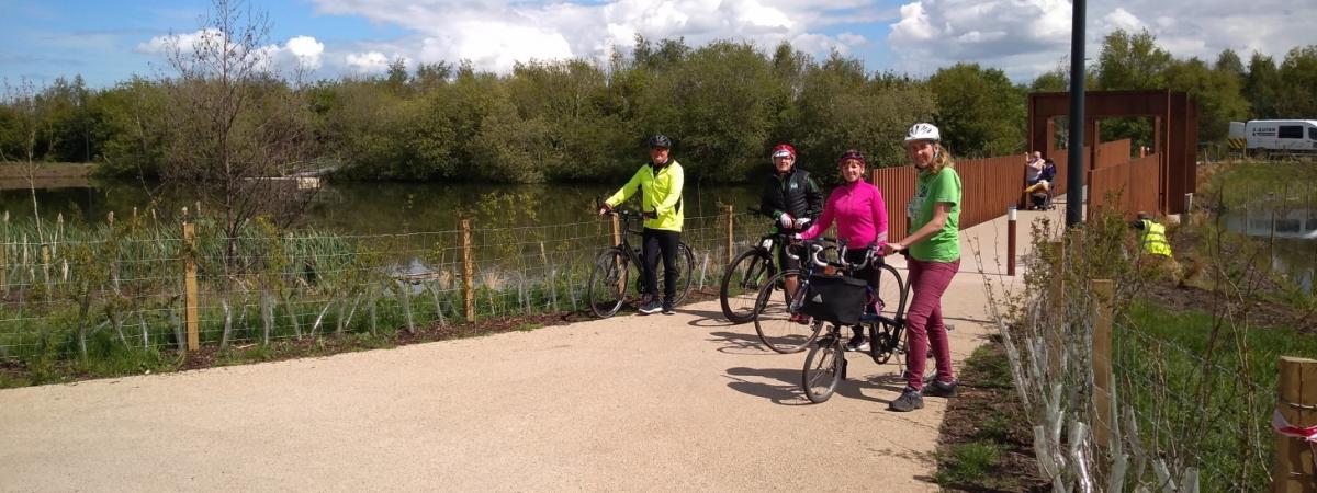 Forth Meadow Community Greenway volunteers standing with their bikes in front of bridge at Springfield Dam as they take part in cycle training