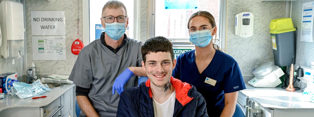 Pictured at the launch of a mobile dental health clinic provided by Dentaid The Dental Charity and staffed by volunteers from Bupa Dental Care to provide oral health care for people supported by Simon Community NI are clinician Paul Blundell, patient Curtis and clinician Teona Baillie. The clinic will offer free emergency care and dental health advice at Simon Community sites in Belfast, Bangor and Armagh every month for the rest of the year. 