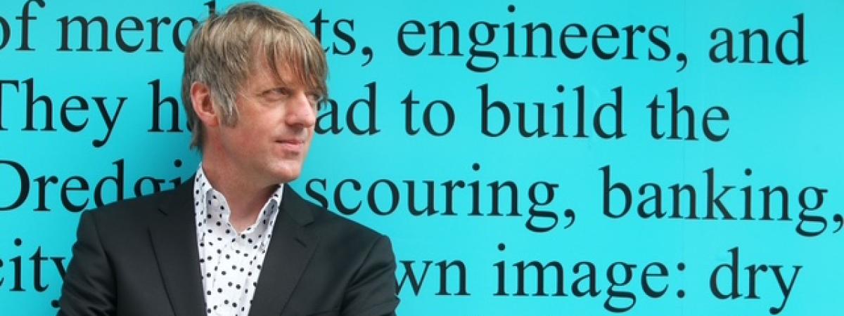 Author Glenn Patterson leans against the backdrop of a quote from his debut novel, 'Fat Lad.'