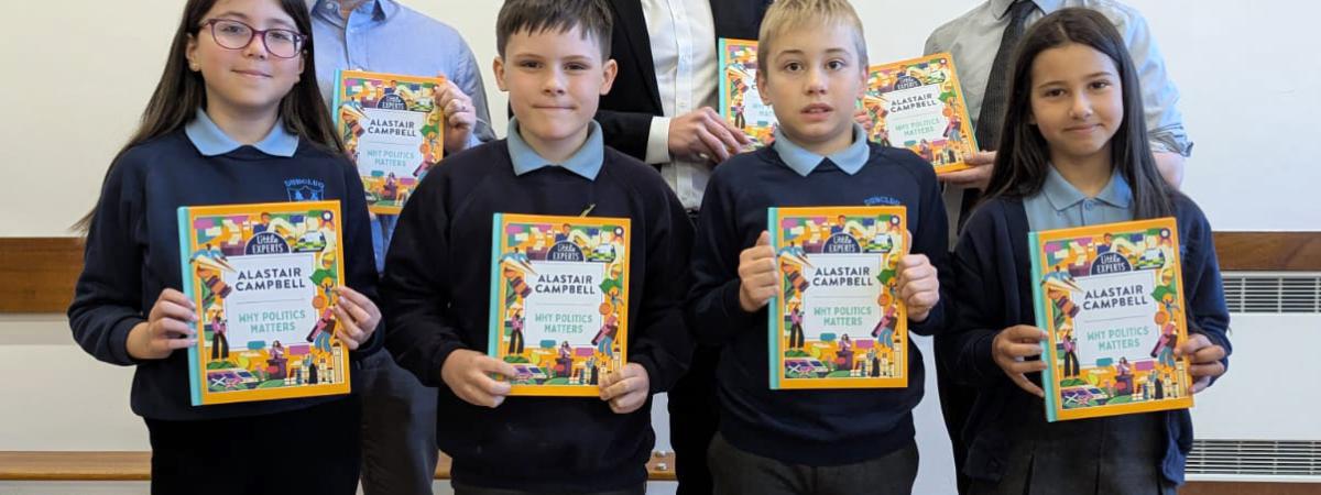 Pinsent Masons’ Senior Associate Matthew McMurray (back row, centre) presents copies of Alastair Campbell’s ‘Why Politics Matters’ book to pupils at Dunclug Primary School. They are joined by school principal Alastair Beacom (R) and teacher Scott Marcus.