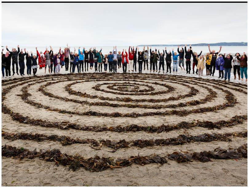 Group of people on a beach with a seaweed labyrinth at an Eden Project community cmap