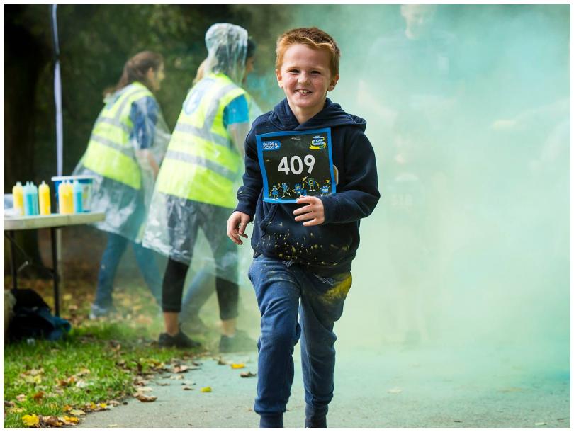 Young boy running through coloured powder