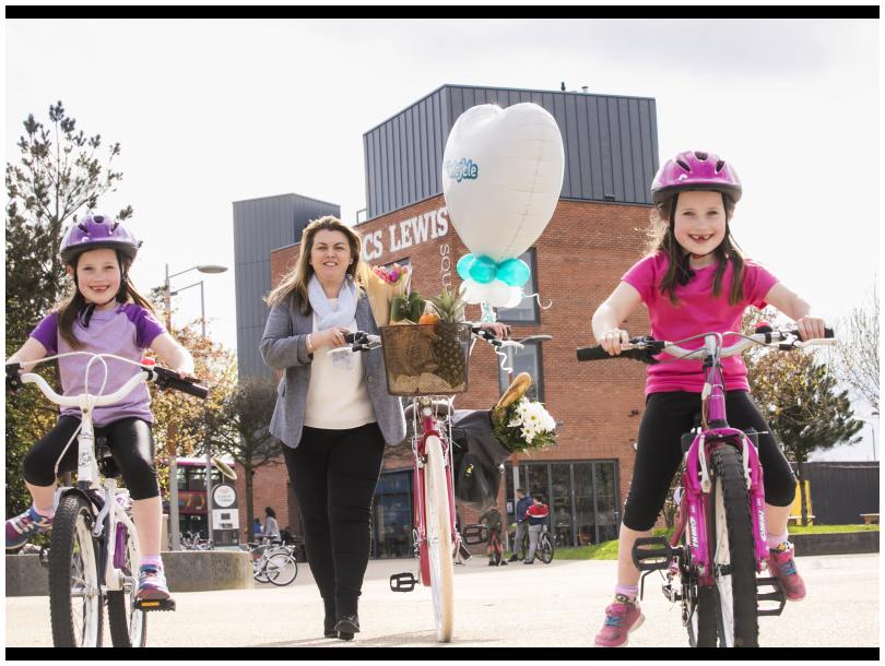 Lorraine Patterson walking her bike with her twin daughters Grace and Lily on their bikes at CS Lewis Square