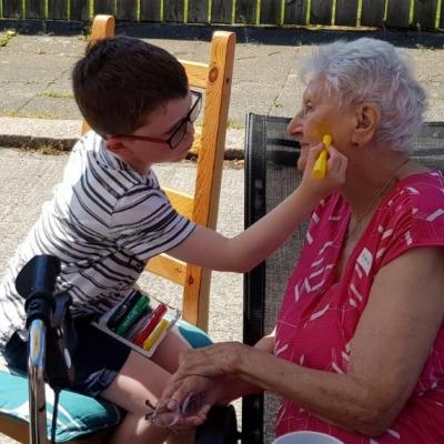 little boy paints older disabled womans face at street party  held as part of The Big Lunch