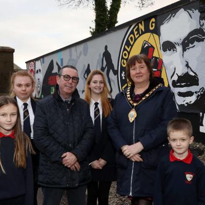 Dave ‘Boy’ McCauley and Mid and East Antrim Mayor, Cllr Maureen Morrow alongside pupils from Moyle Primary School and Larne High School reveal the new mural.